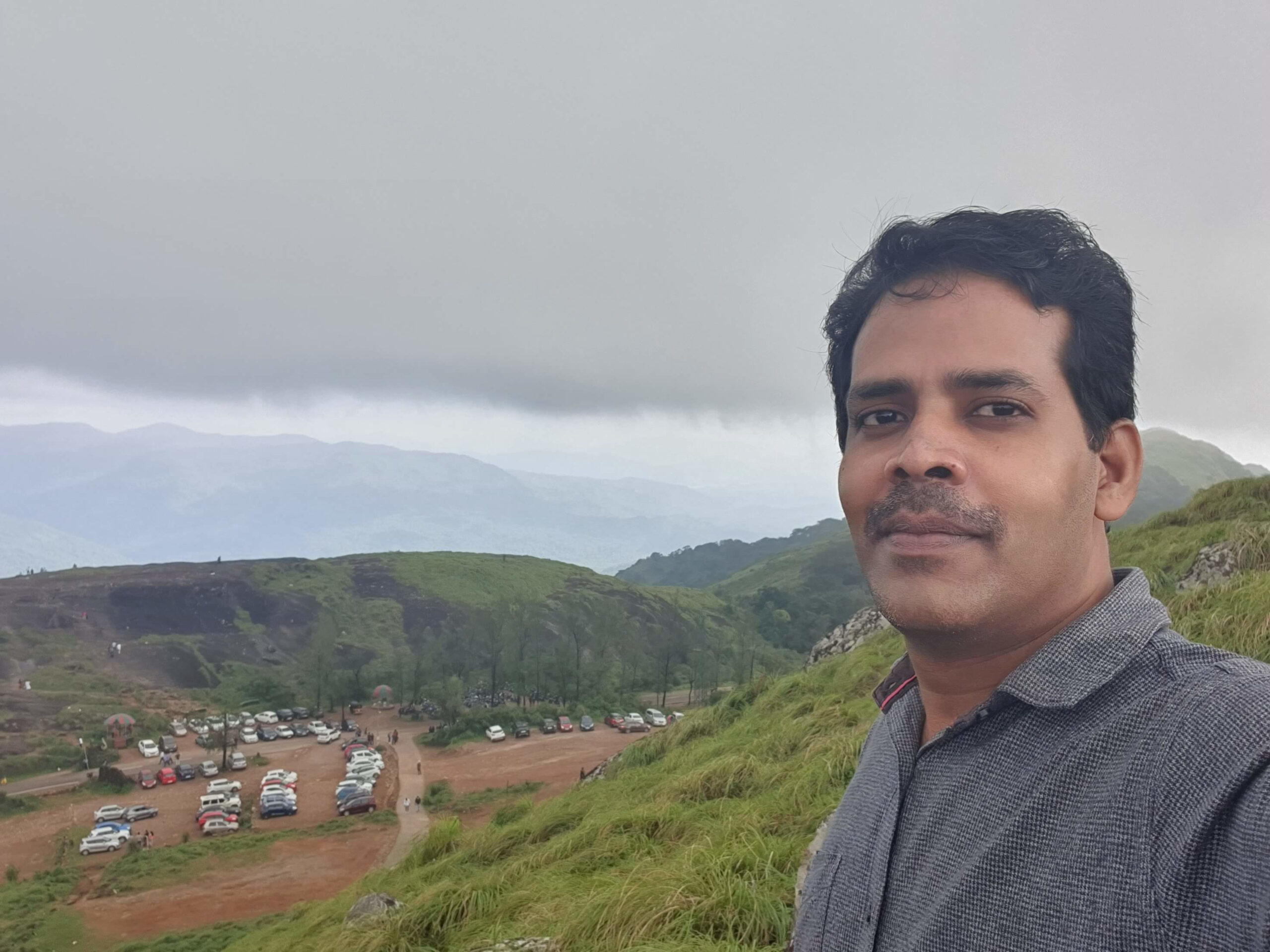 Curvy mountain road surrounded by thick green forest leading up to Ponmudi